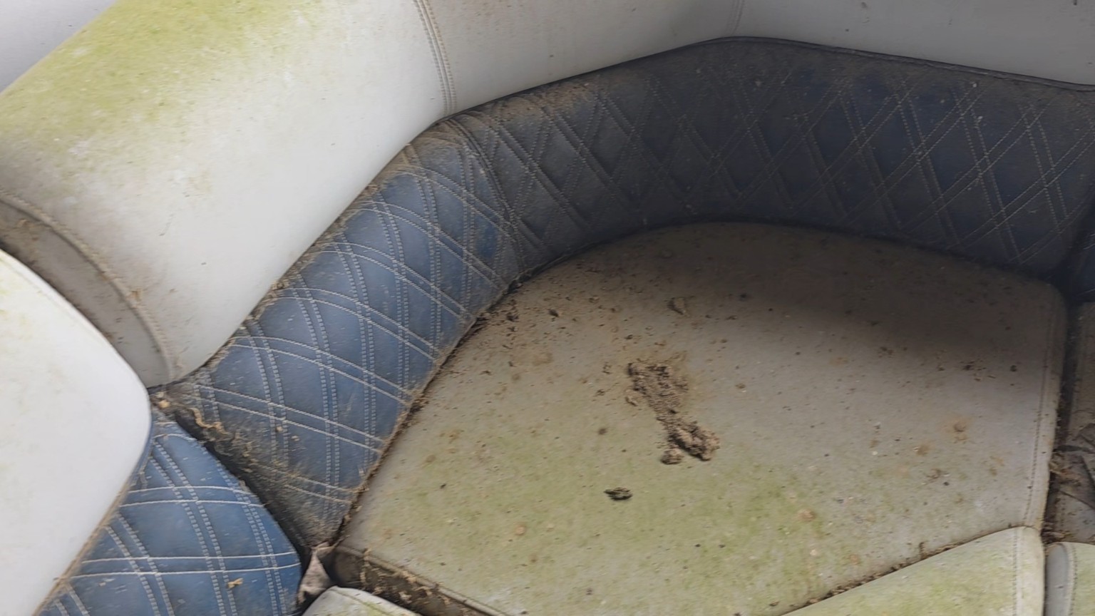 Before boat seating cleaning: white and navy upholstery with green discoloration, dirt and debris