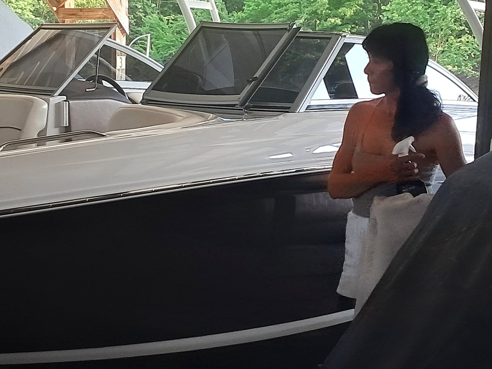 Boat care underway beside a white boat in a covered dock