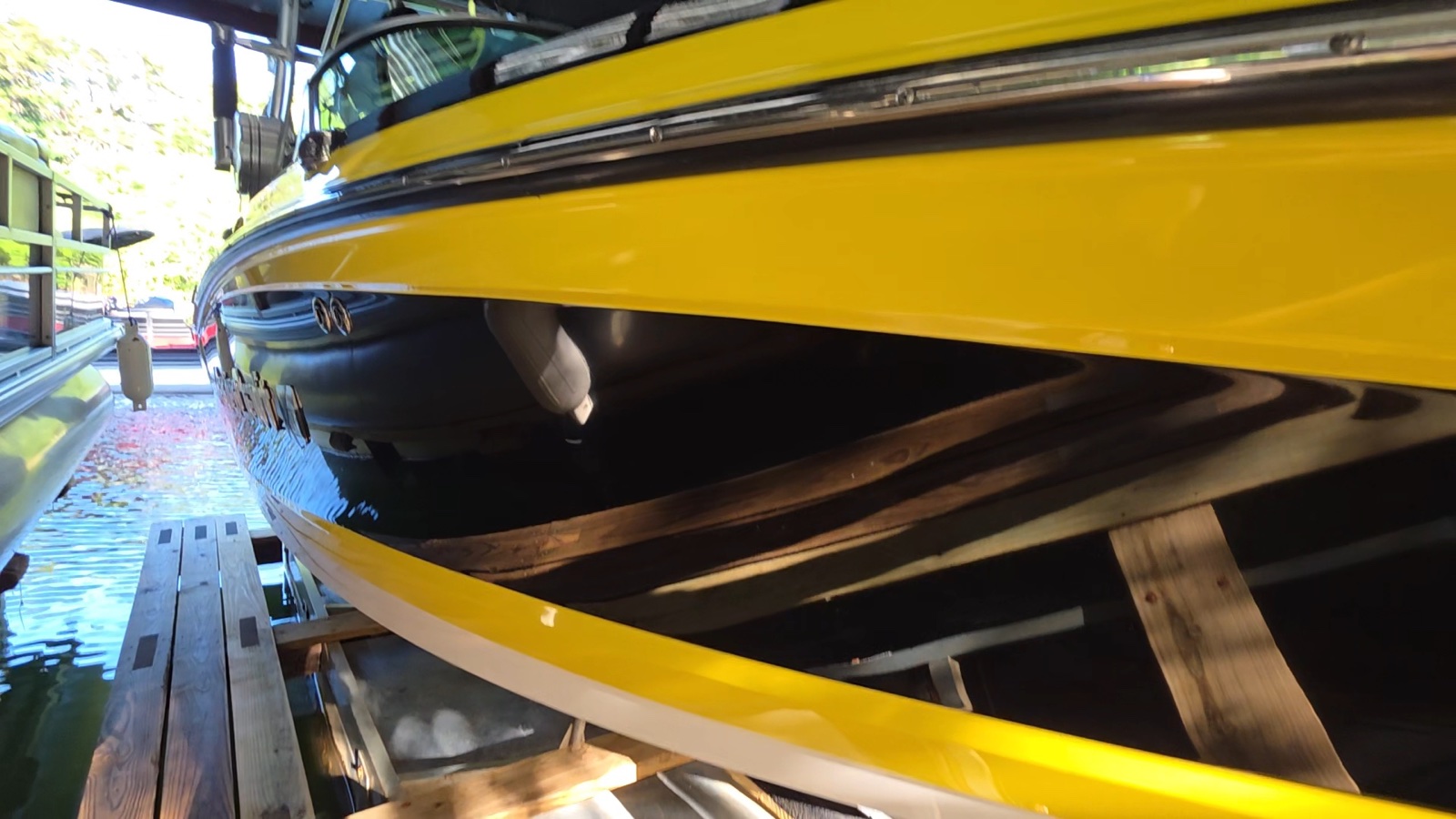 Polished yellow and black MasterCraft boat hull reflecting the surrounding dock